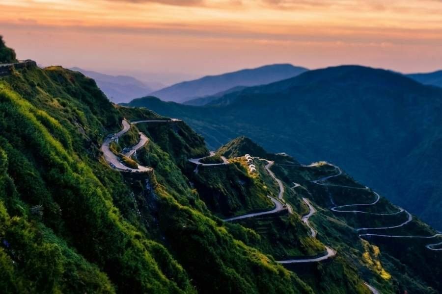 A winding Sikkim mountain road beneath a golden sky